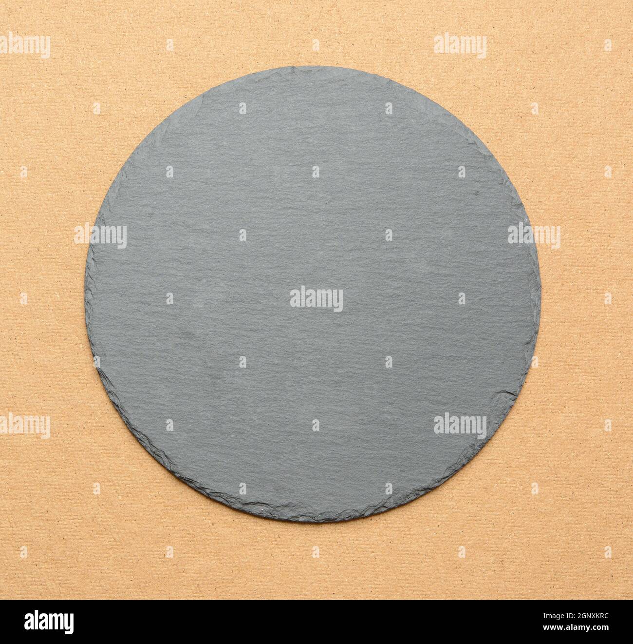 empty black round slate kitchen board on a brown background, top view Stock Photo