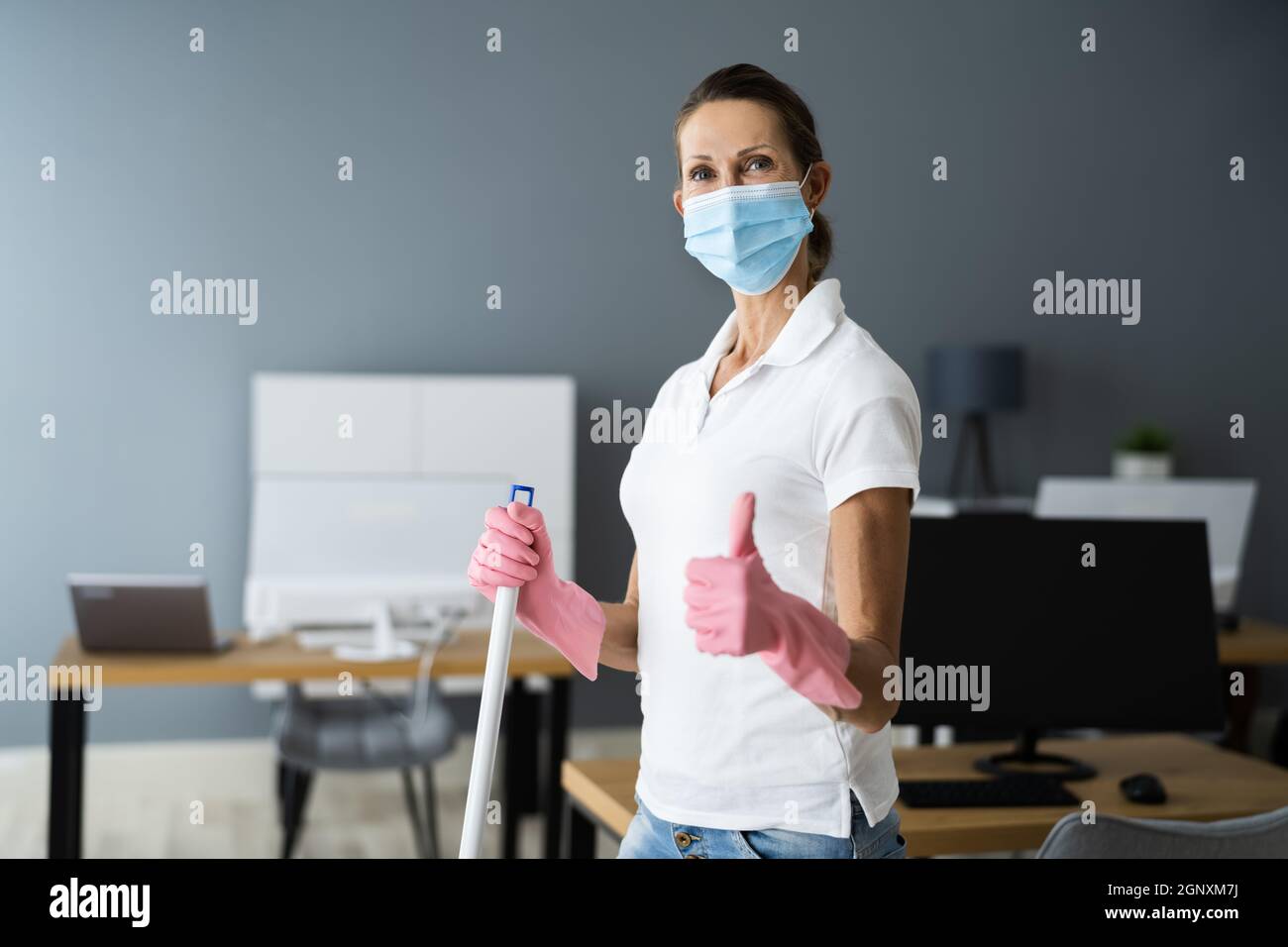 Female Janitor Mopping Floor In Face Mask In Office Stock Photo