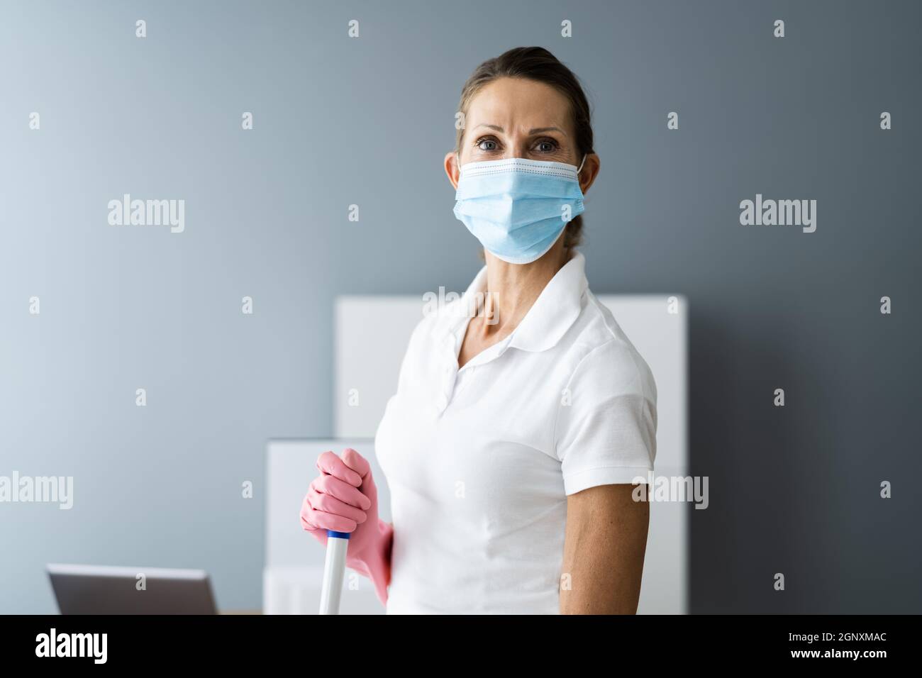 Female Janitor Mopping Floor In Face Mask In Office Stock Photo