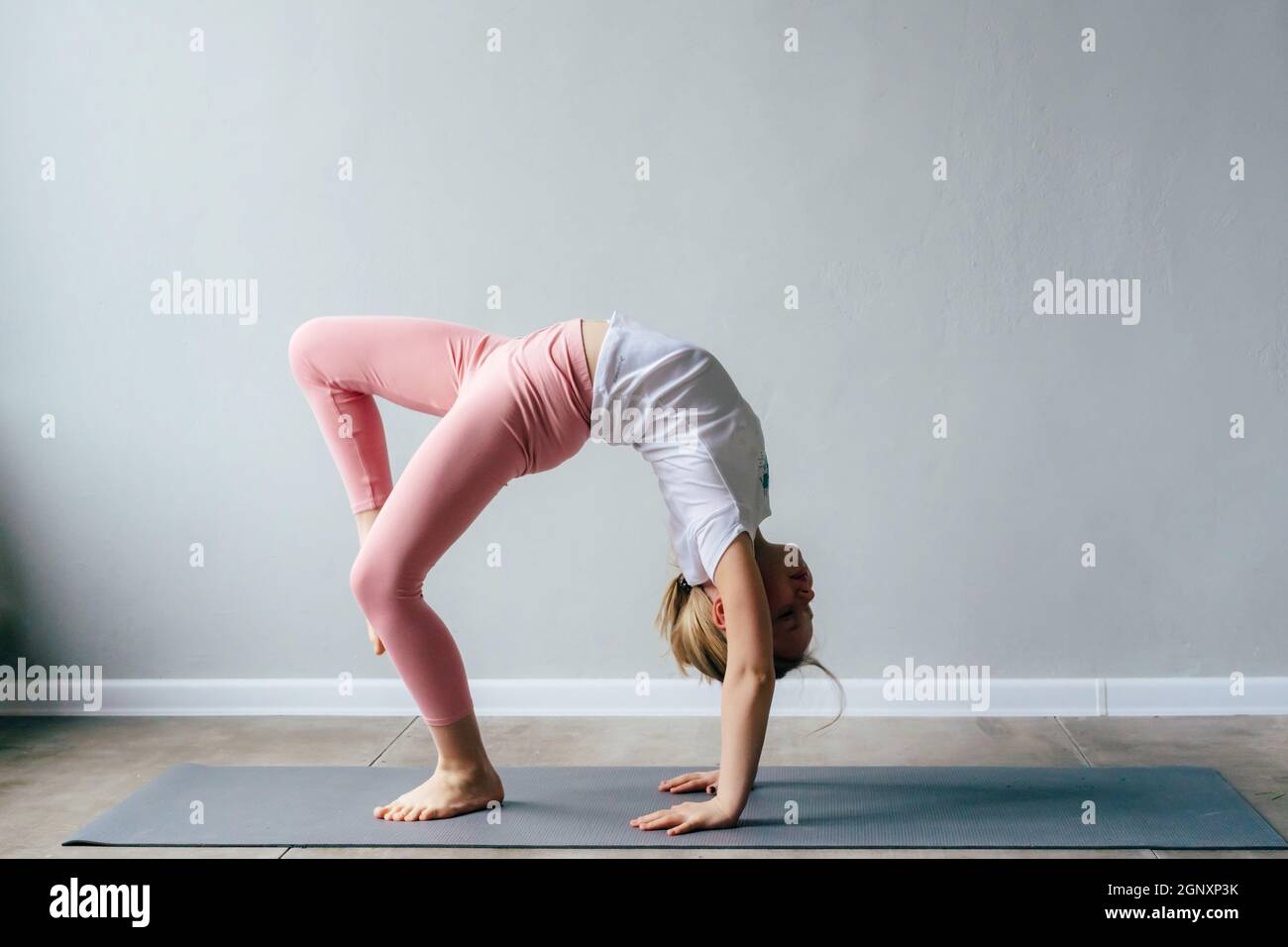 Flexible girl in an acrobatic pose in the gym Stock Photo