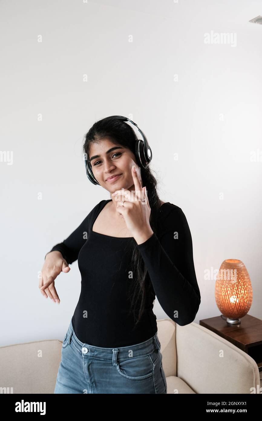 Vertical shot of a ygirl dancing in a room with headphones Stock Photo
