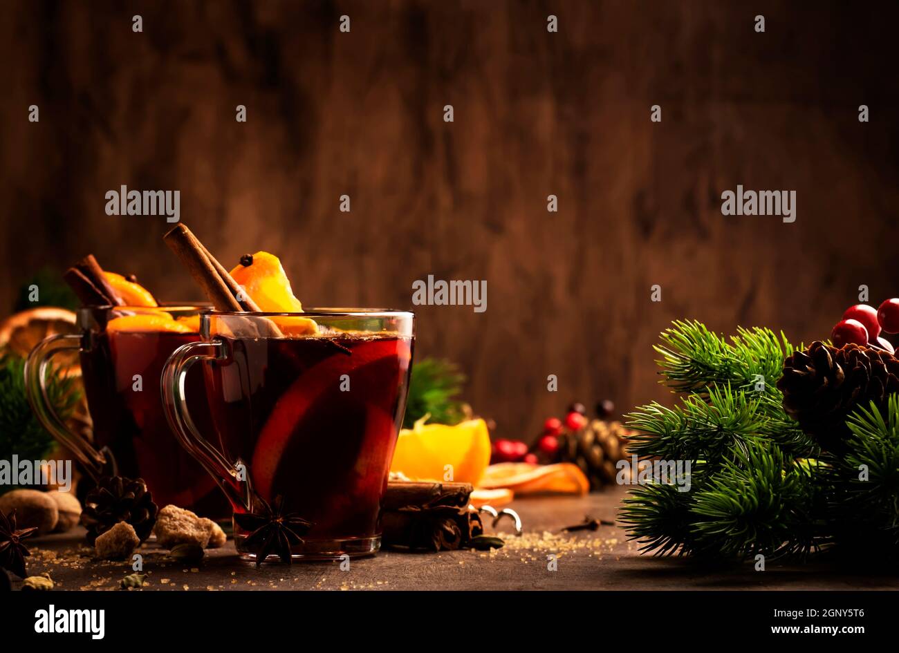 Winter hot mulled red wine in glass cup on wooden rustic table. Traditional Christmas or New Year drink in festive table setting Stock Photo