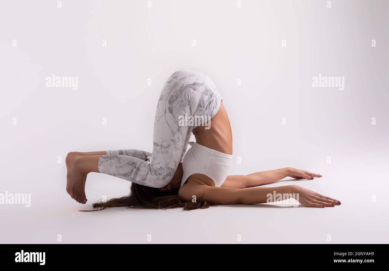 Sporty young woman doing yoga practice isolated on white background ...