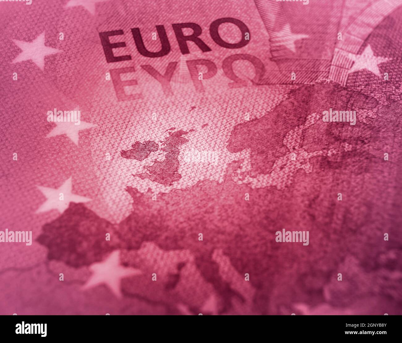Abstract design. Unfocused Euro bill close up detail of Europe map with focus on Great Britain. Red color tone. Stock Photo