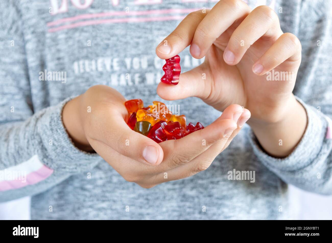 A girl holds a gummy bear in her hand, wants to eat jelly sweets. Close