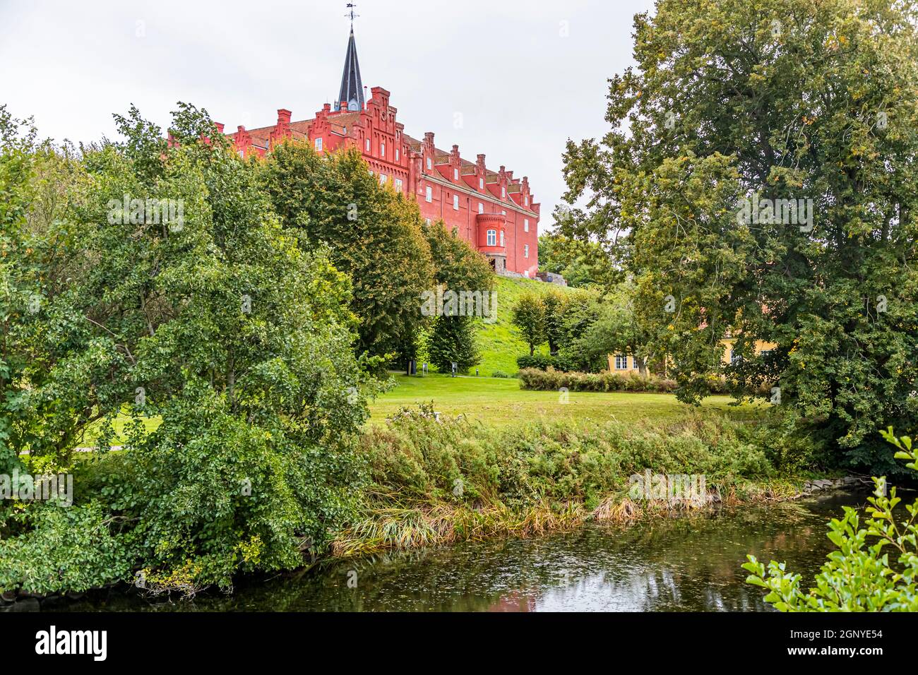 Tranekær Castle is glowing red in the park. The castle has existed on this site since the 13th century and was used as an official residence by the officials of the Danish king on the island of Langeland, Denmark Stock Photo