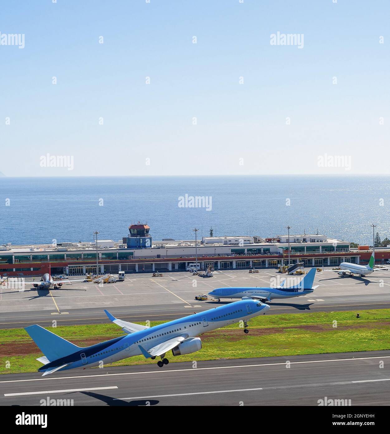 Airplanes taking off at runway of Madeira International Airport, bright sunshine weather, ocean view in background, Funchal, Portugal Stock Photo