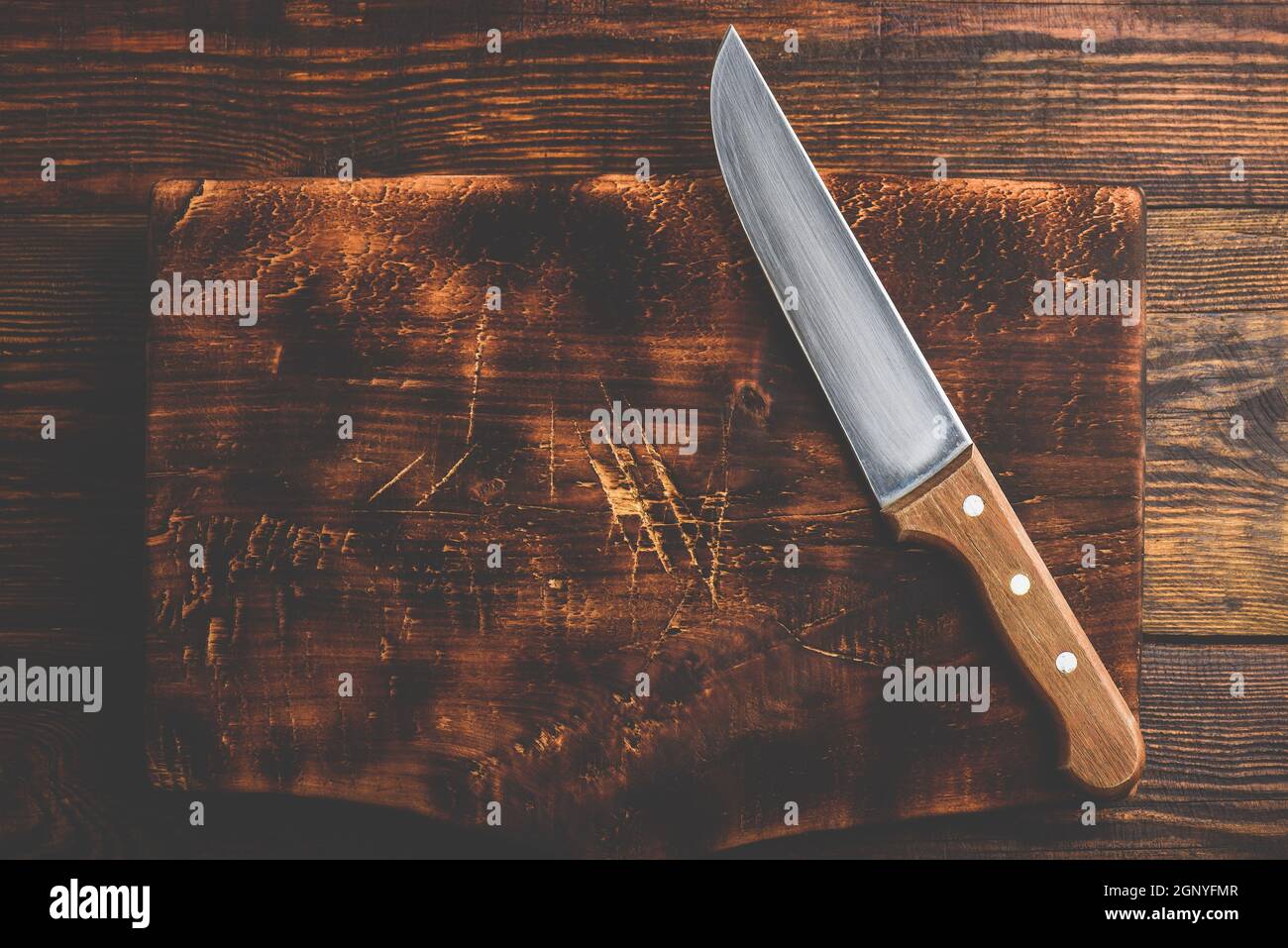 Knife over rustic wooden cutting board Stock Photo