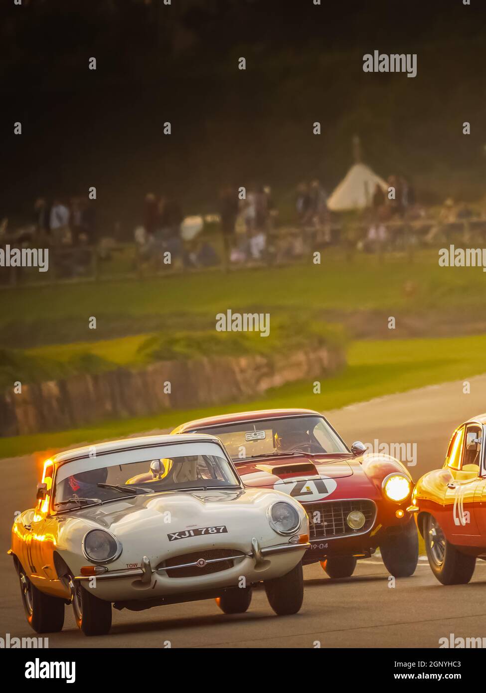 E Type Jaguar and Ferrari 250 racing at sunset at the Goodwood Revival 2021, West Sussex, uk Stock Photo