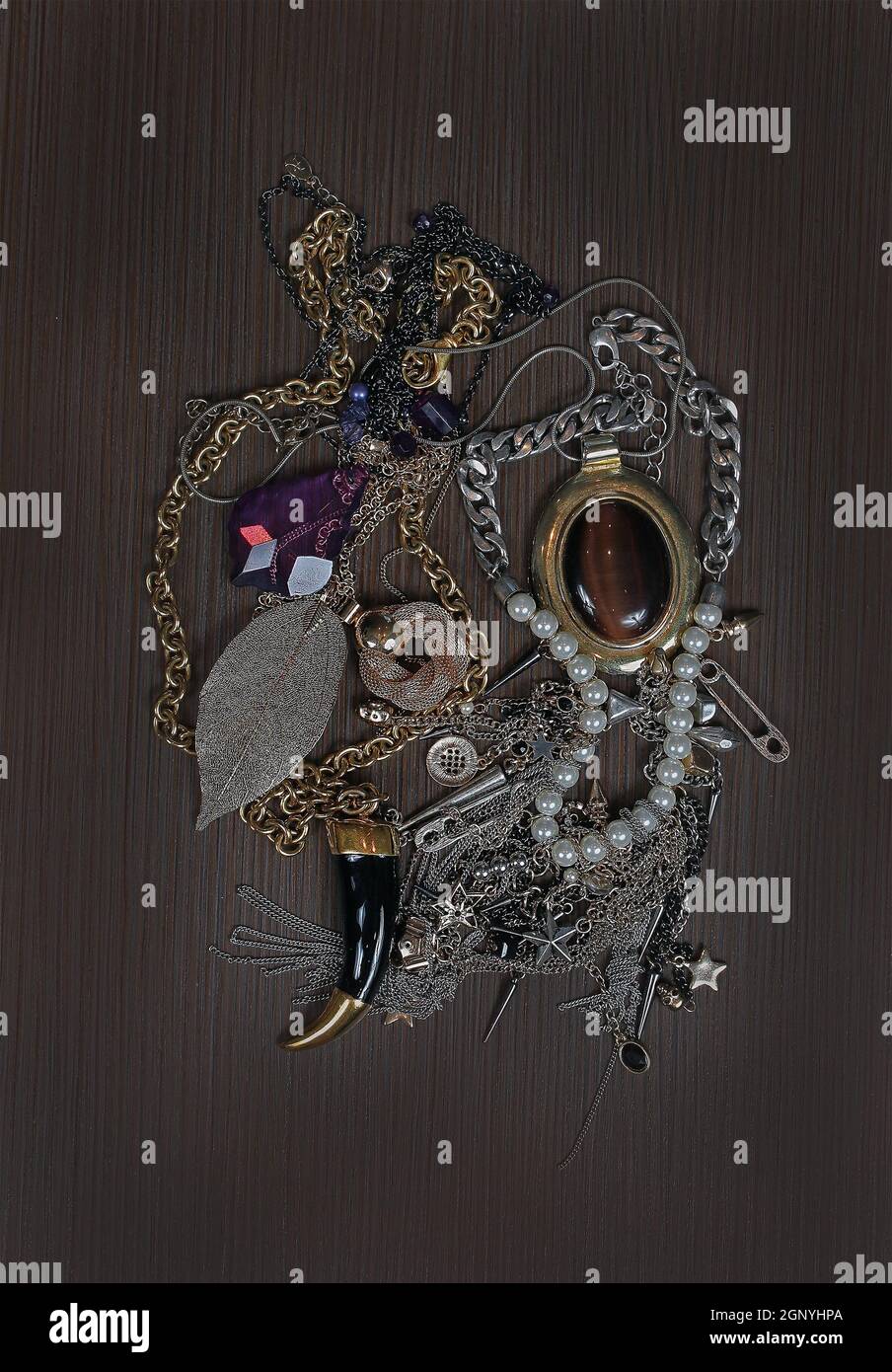 Old fashionable jewelry pile on brown wooden background Stock Photo