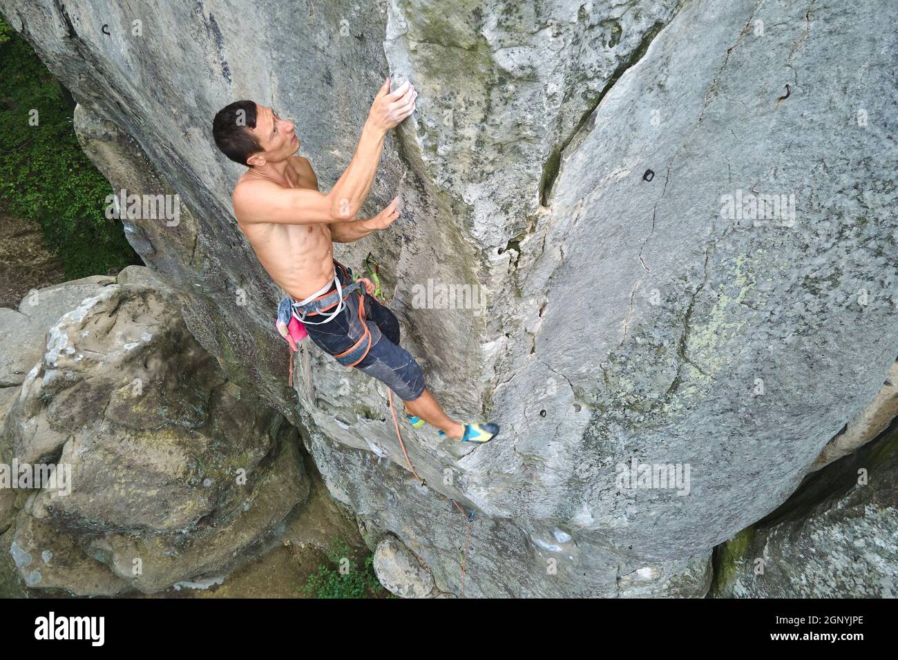 Determined climber clambering up steep wall of rocky mountain ...