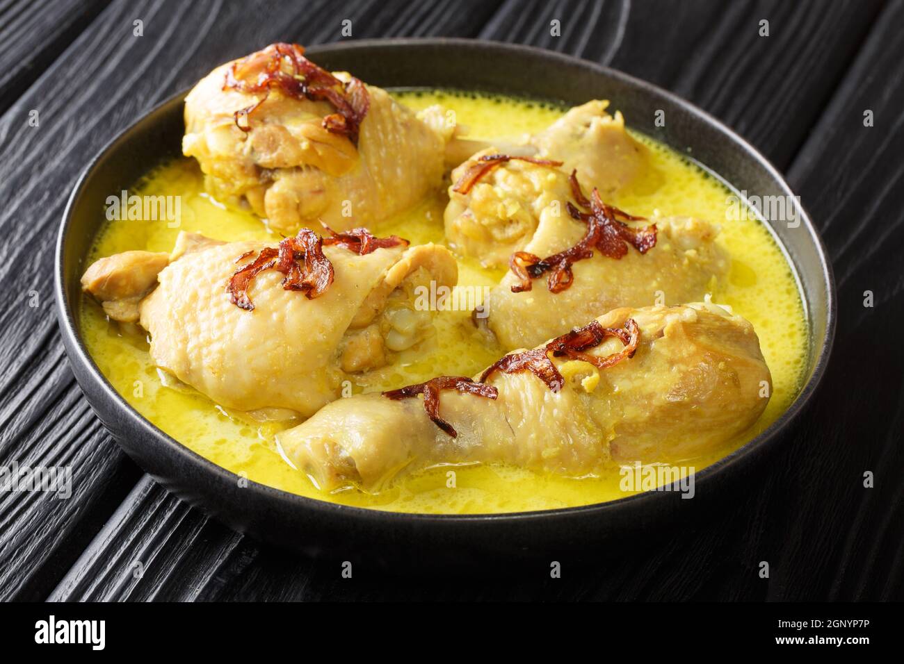 Asian food pieces of chicken stew in coconut milk with spices close-up in a bowl on the table. horizontal Stock Photo