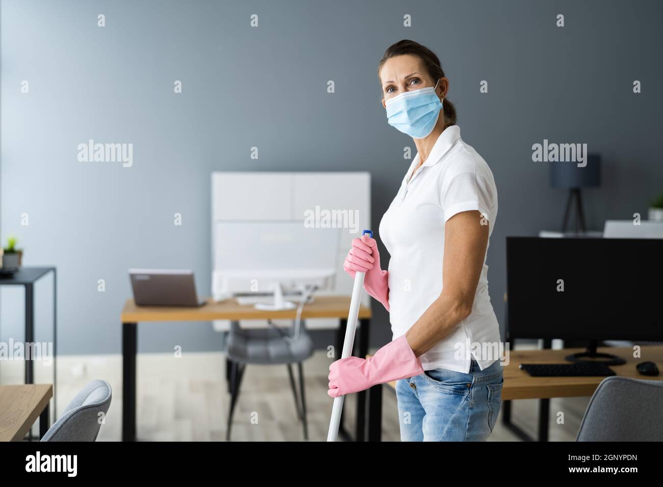 Female Janitor Mopping Floor In Face Mask In Office Stock Photo