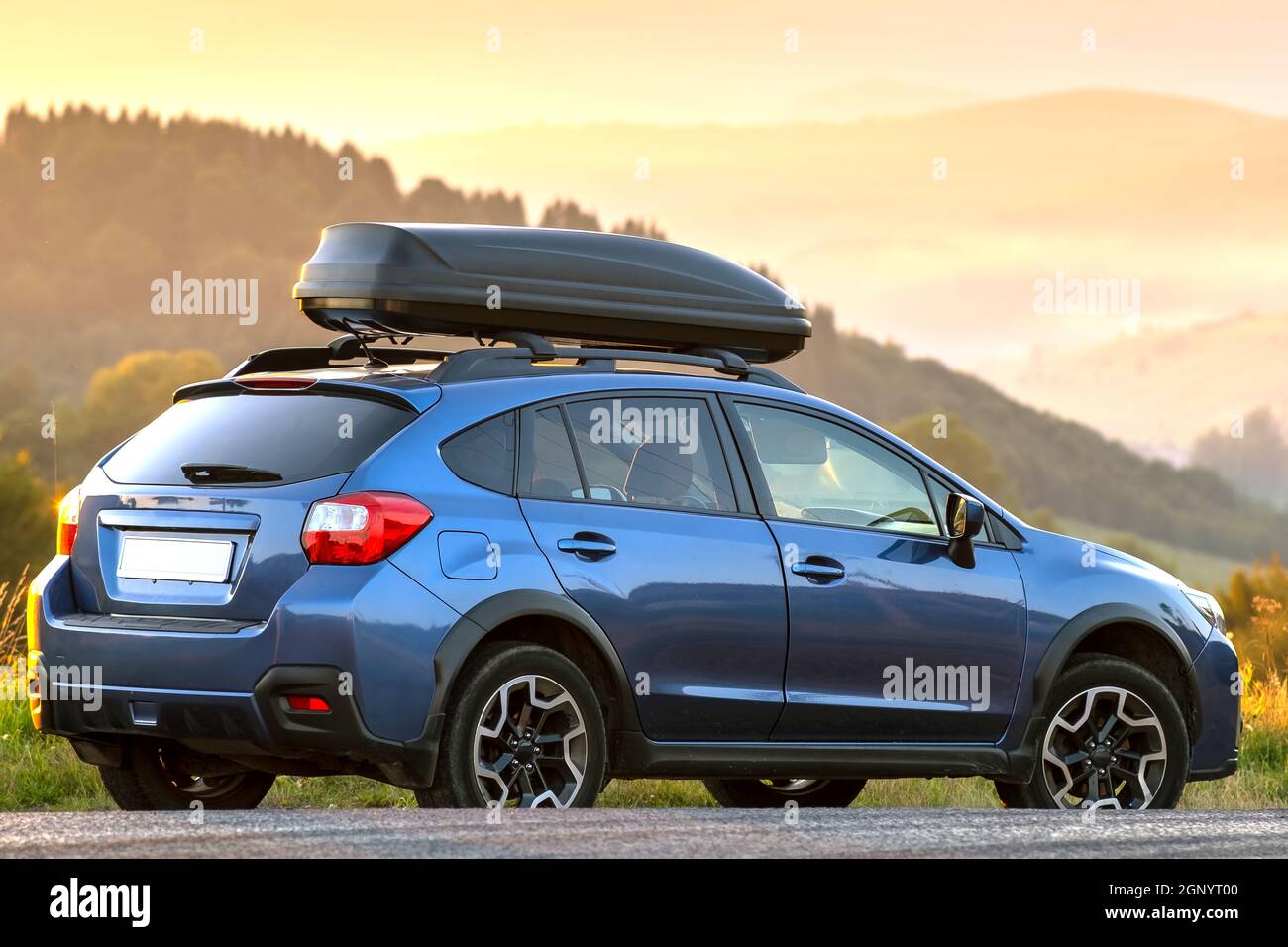 SUV car with roof rack luggage container for off road travelling parked at roadside at sunset. Stock Photo