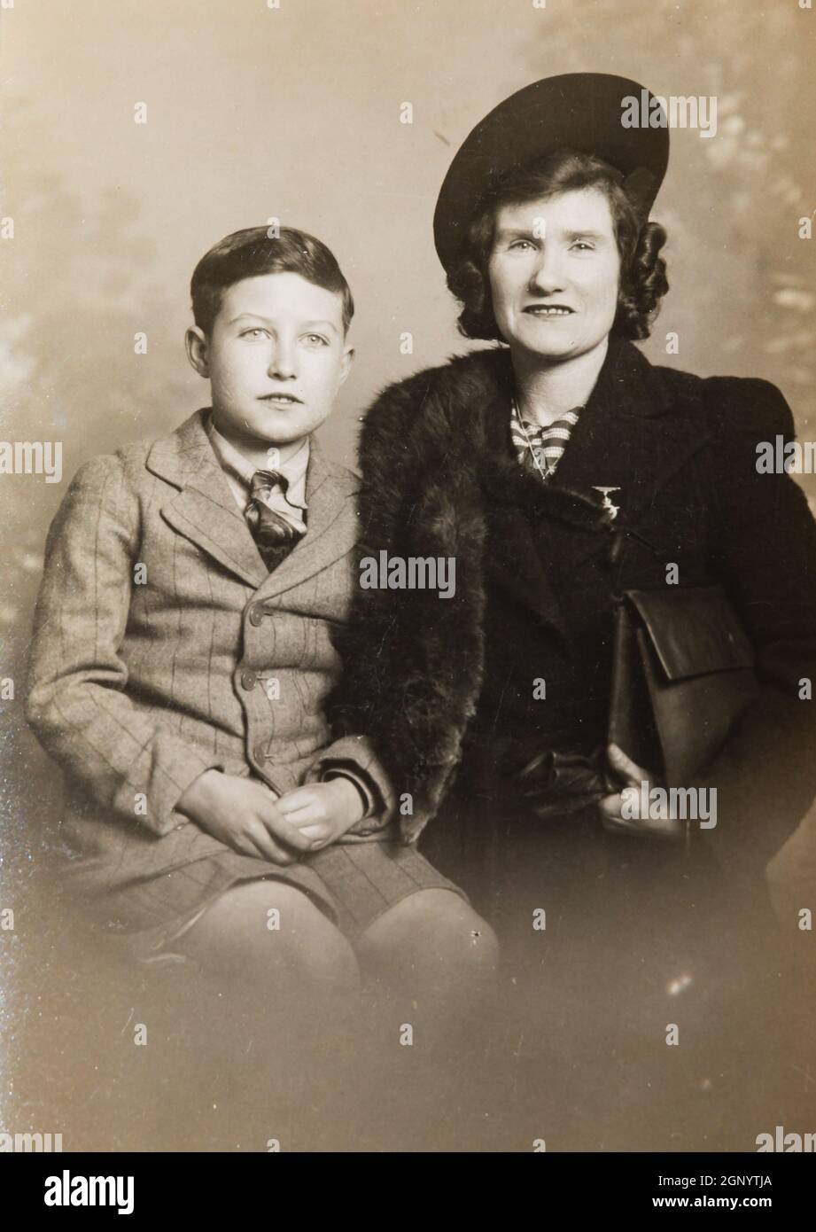 Mother and son sit for a portrait during WW2. 1941. Archive. Old sepia ...