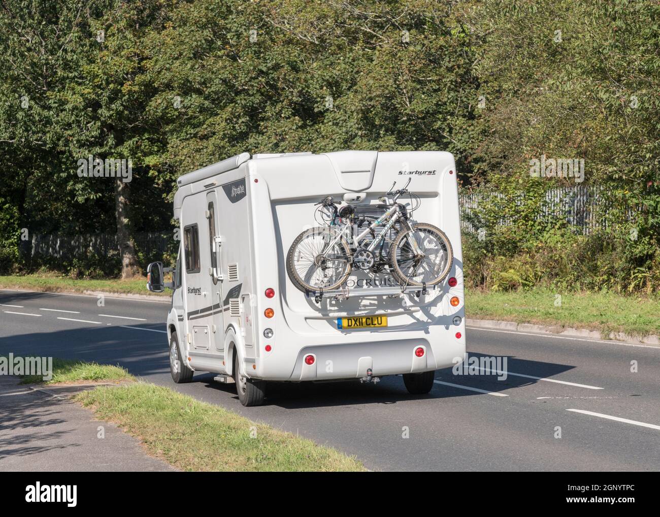 Autocruise Starburst motorhome & mountain bikes travelling downhill on Cornwall country road. For UK motorhomes, UK staycations, alternative holidays. Stock Photo