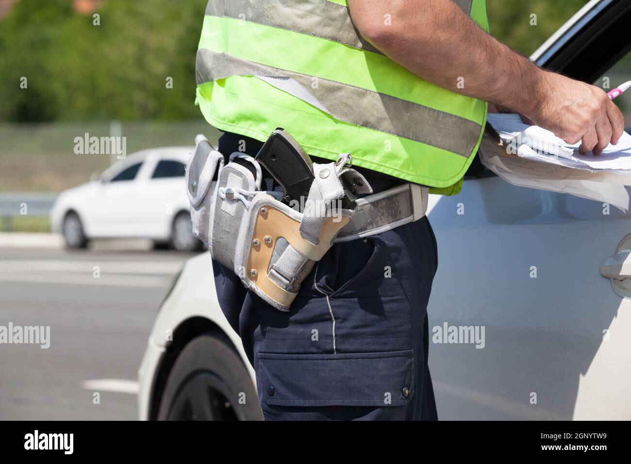 A policeman is writing a ticket for a car driver who was speeding Stock Photo