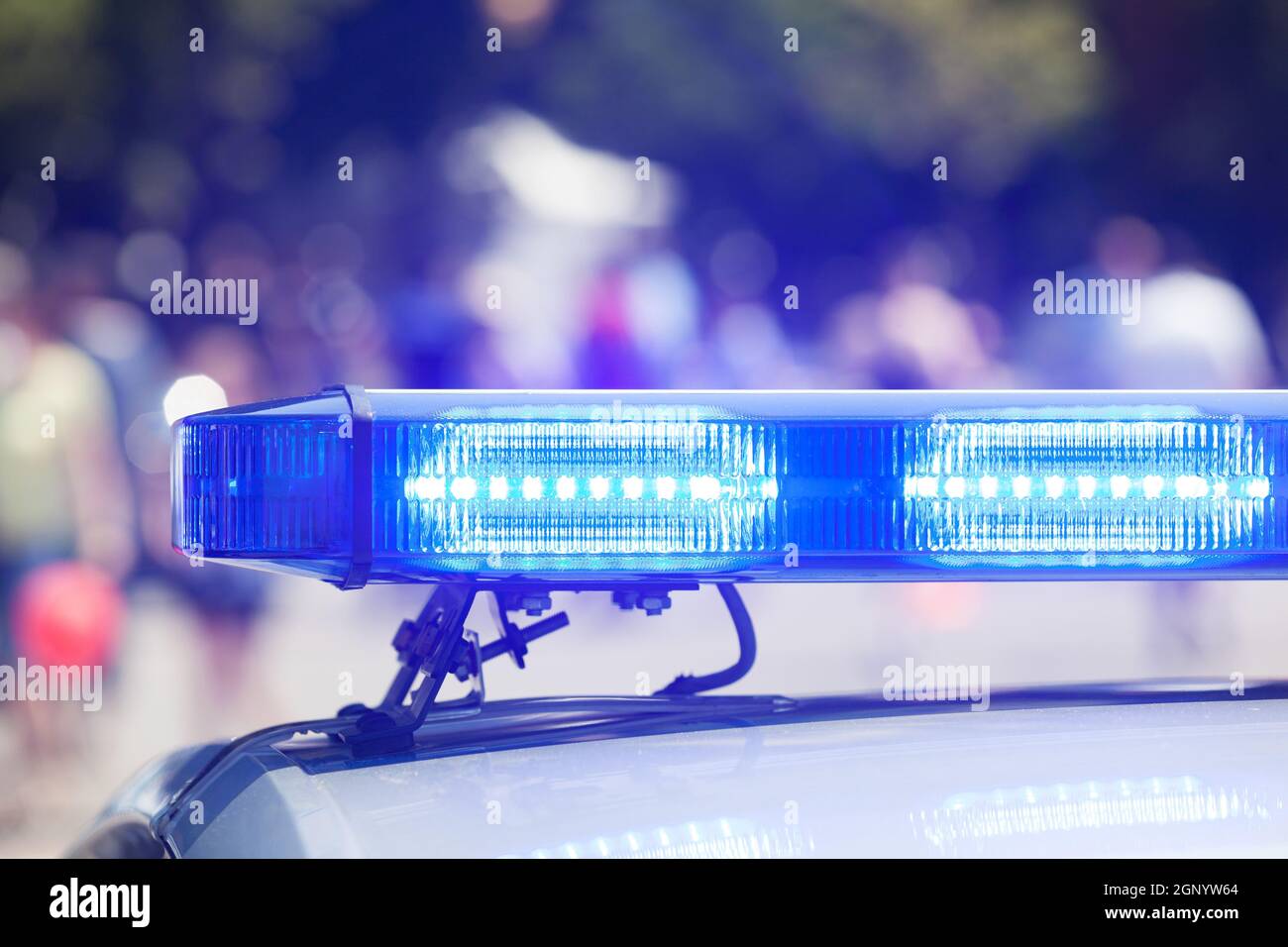 Police car flashing lights in focus, blurred crowd in background Stock