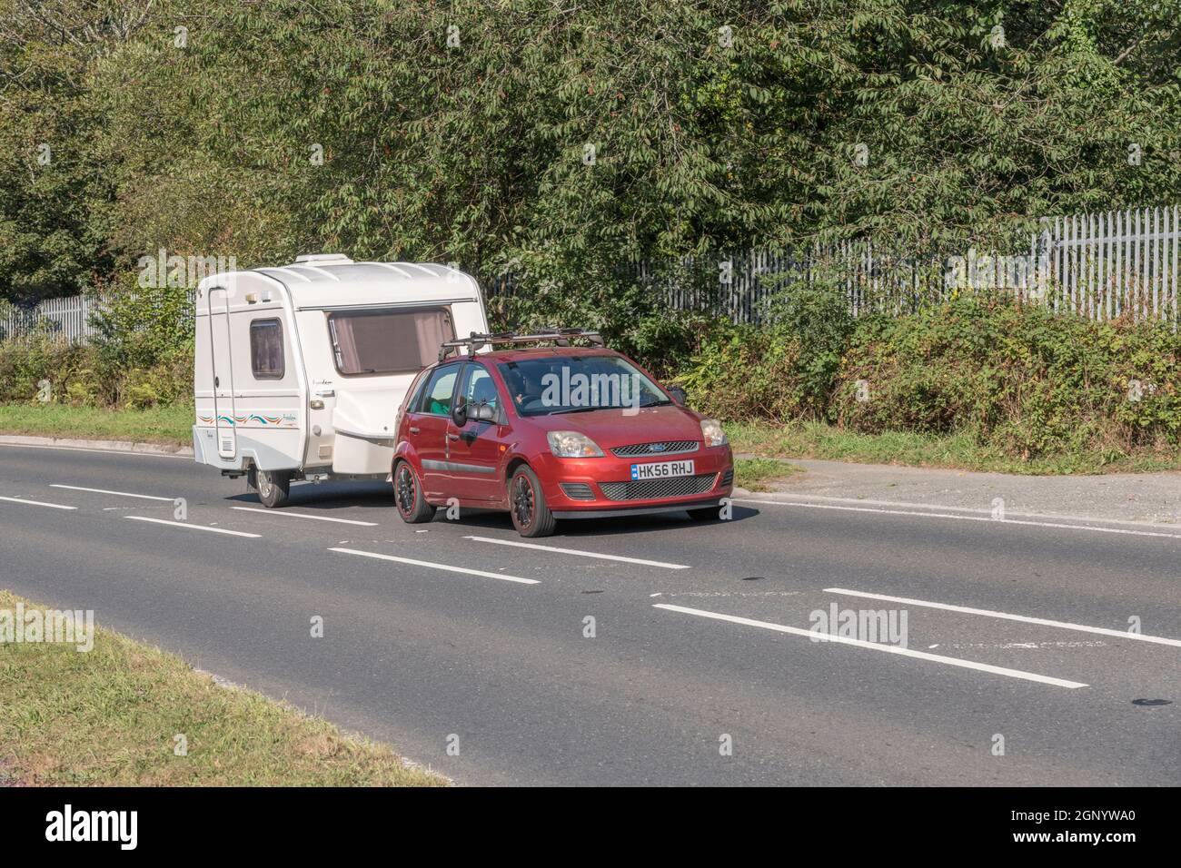 Ford car towing Freedom Twin caravan uphill on country road in Cornwall. For UK caravans, campervans, staycations in UK, alternative holidays. Stock Photo
