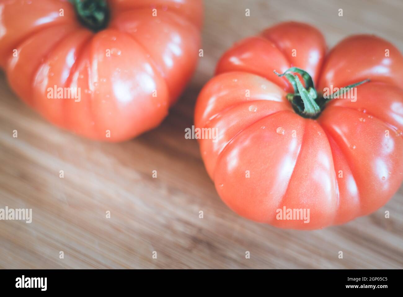 Close up picture of oxheart tomatoes on a bamboo wood plate. Stock Photo