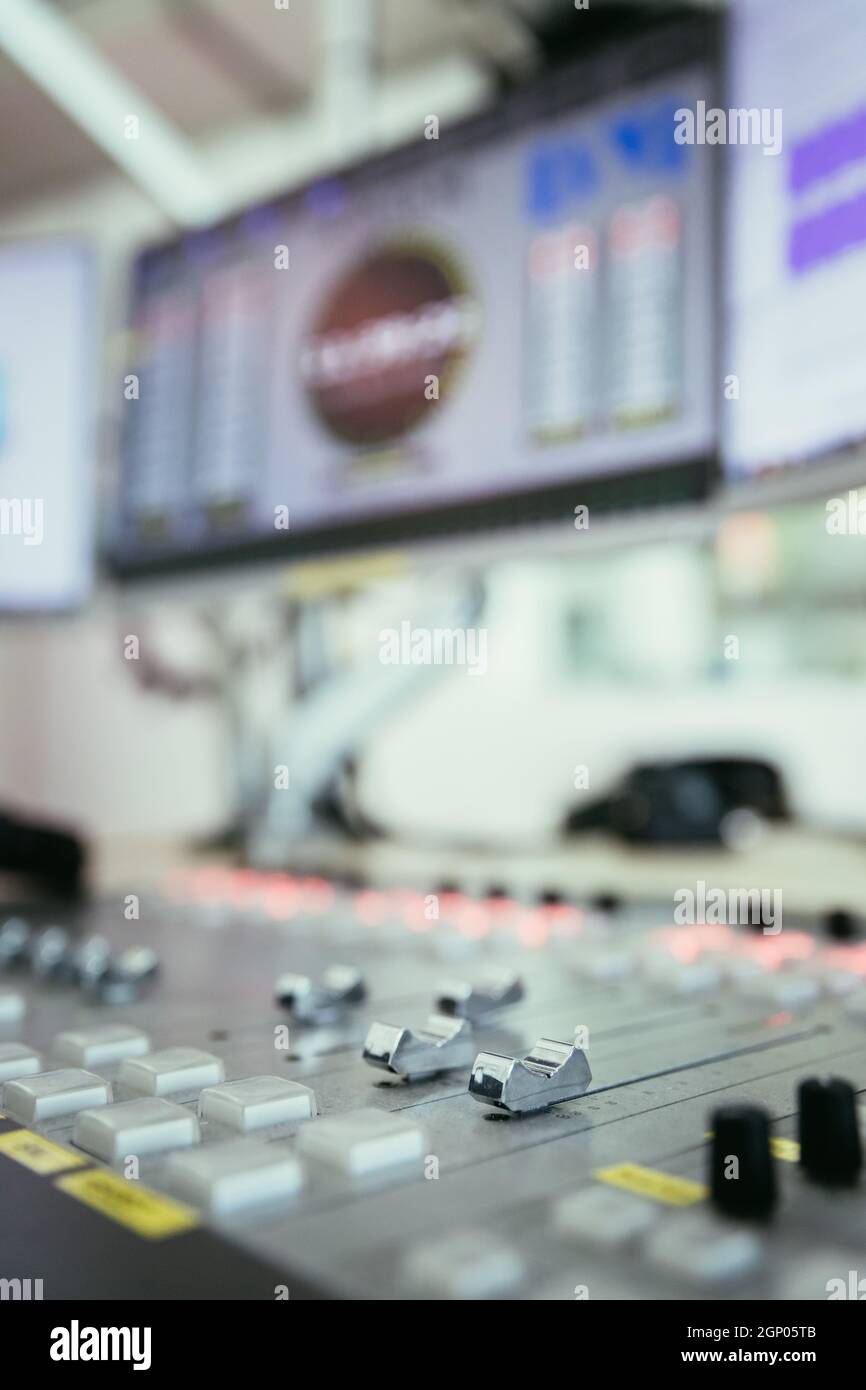 Close up picture of a soundboard in a broadcasting studio, computers in