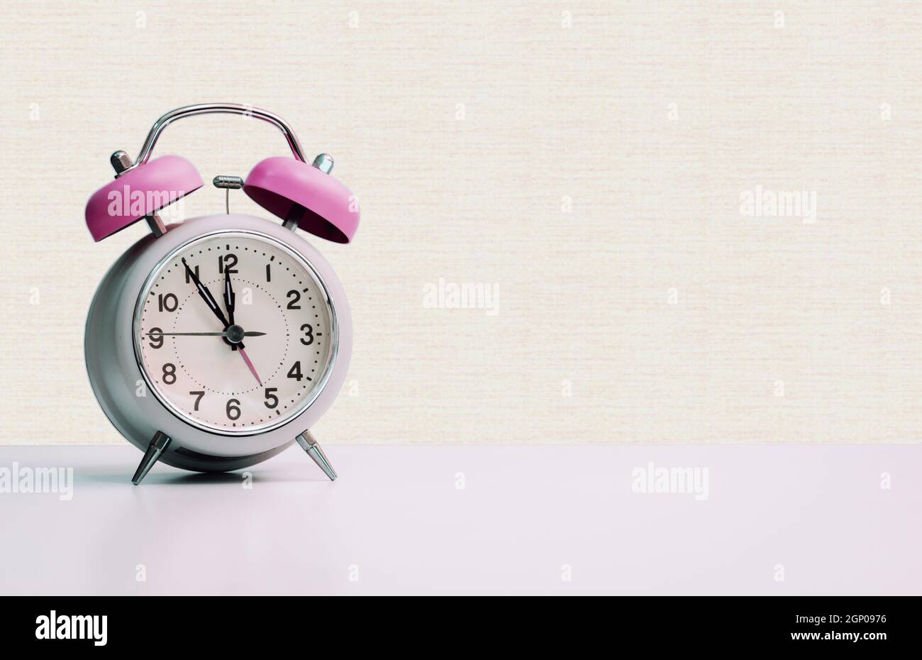 Retro styled white alarm clock, isolated and copy space, pink yellow Stock Photo