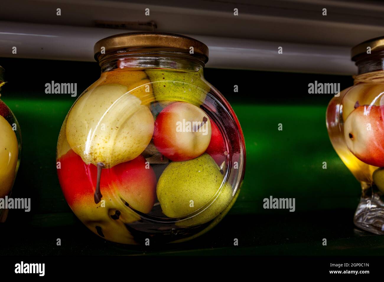 Preserved canned apples and pear in a big glass jar on the shelf Stock Photo