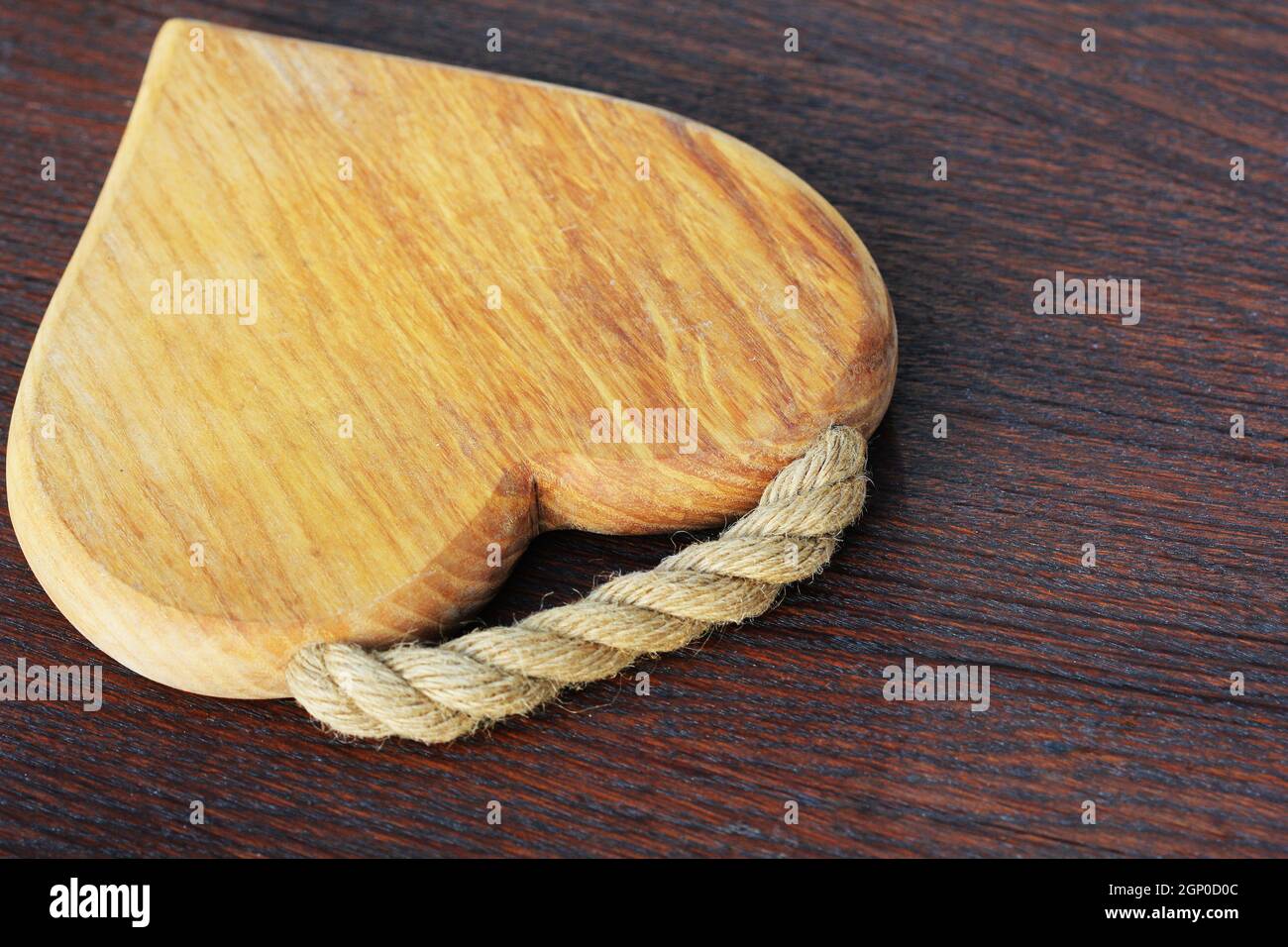 Heart shaped cutting board on rustic wooden background . Stock Photo