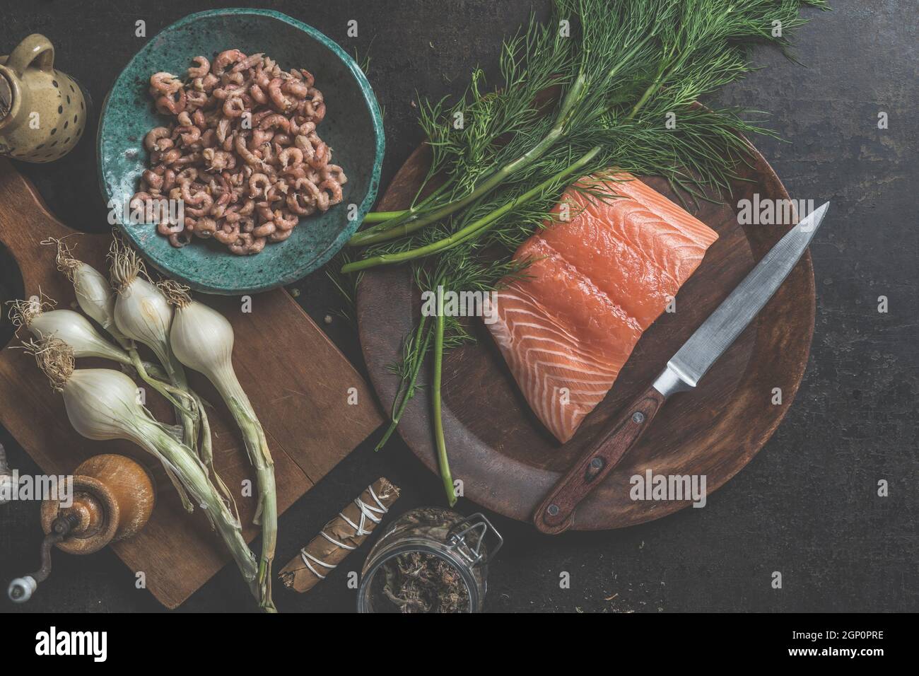 Raw portioned salmon fillet on wooden plate with knife, dill and north sea crab and other ingredients for healthy cooking. Top view Stock Photo