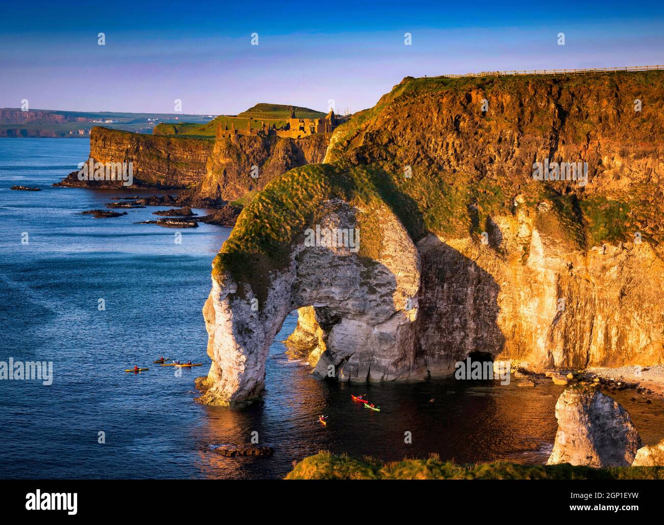 Canoeists under the sea arch at Dunluce Castle on the North coast of County Antrim, Northern Ireland Stock Photo