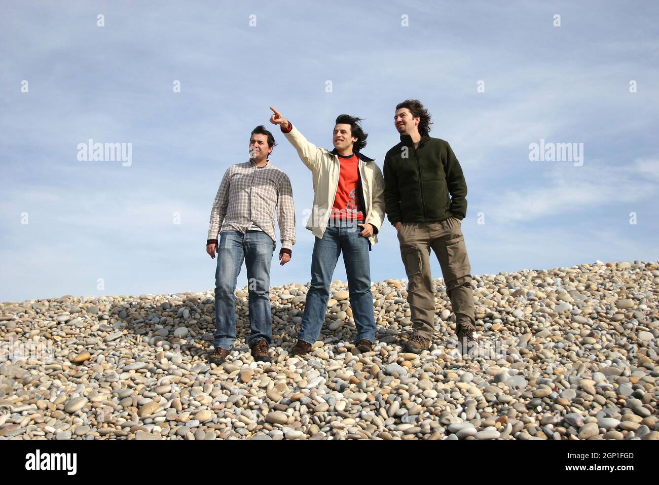 three casual young men at the beach, isolated on blue background Stock Photo