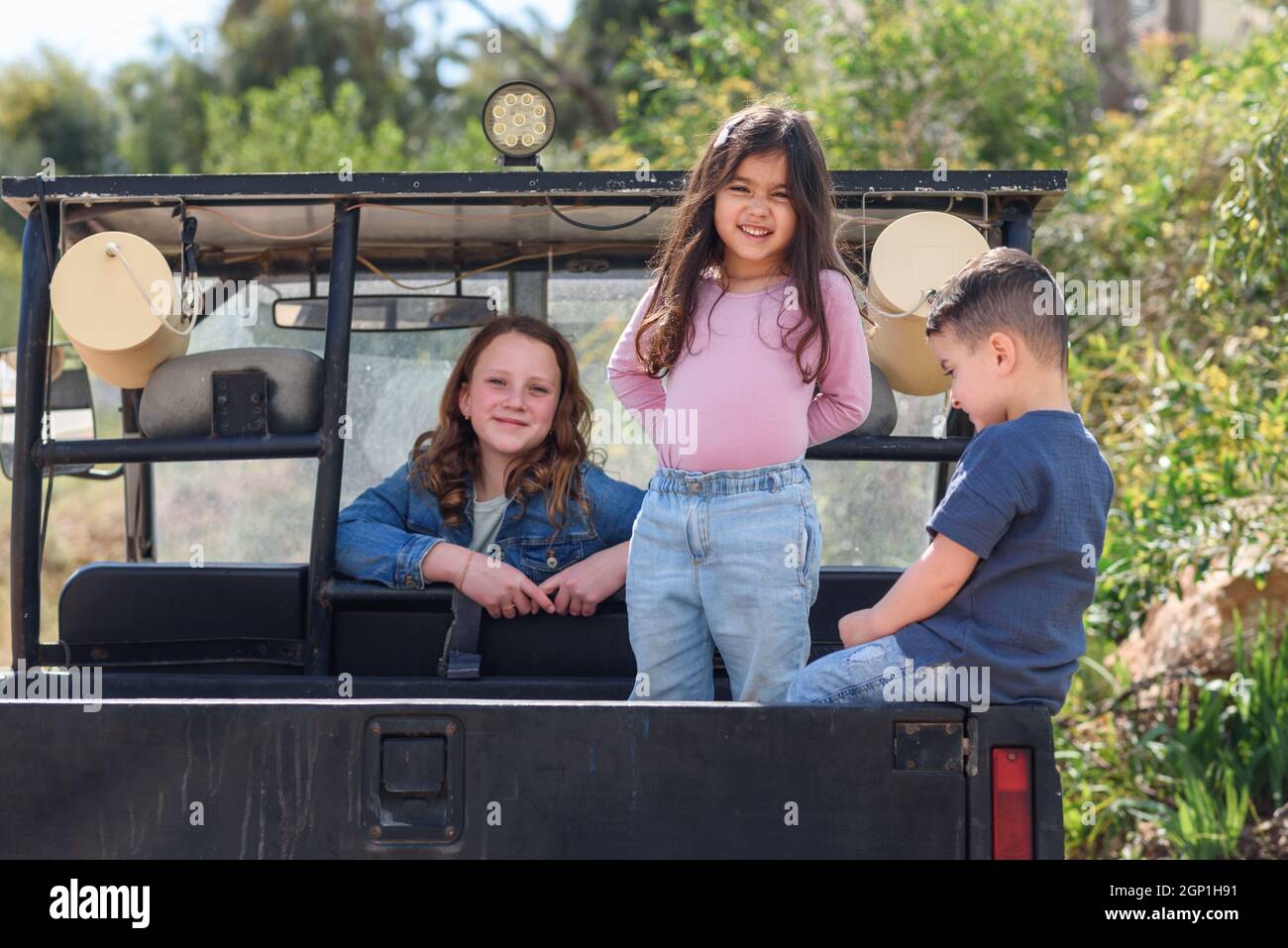Smiling children having fun in the back of their pickup truck enjoying