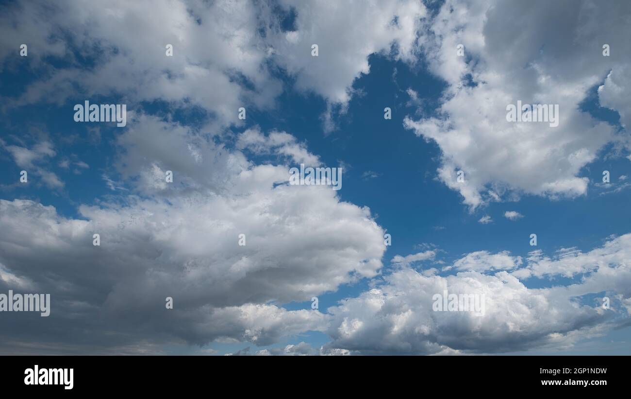 Low angle shot of beautiful thick clouds hovering over a bright blue ...