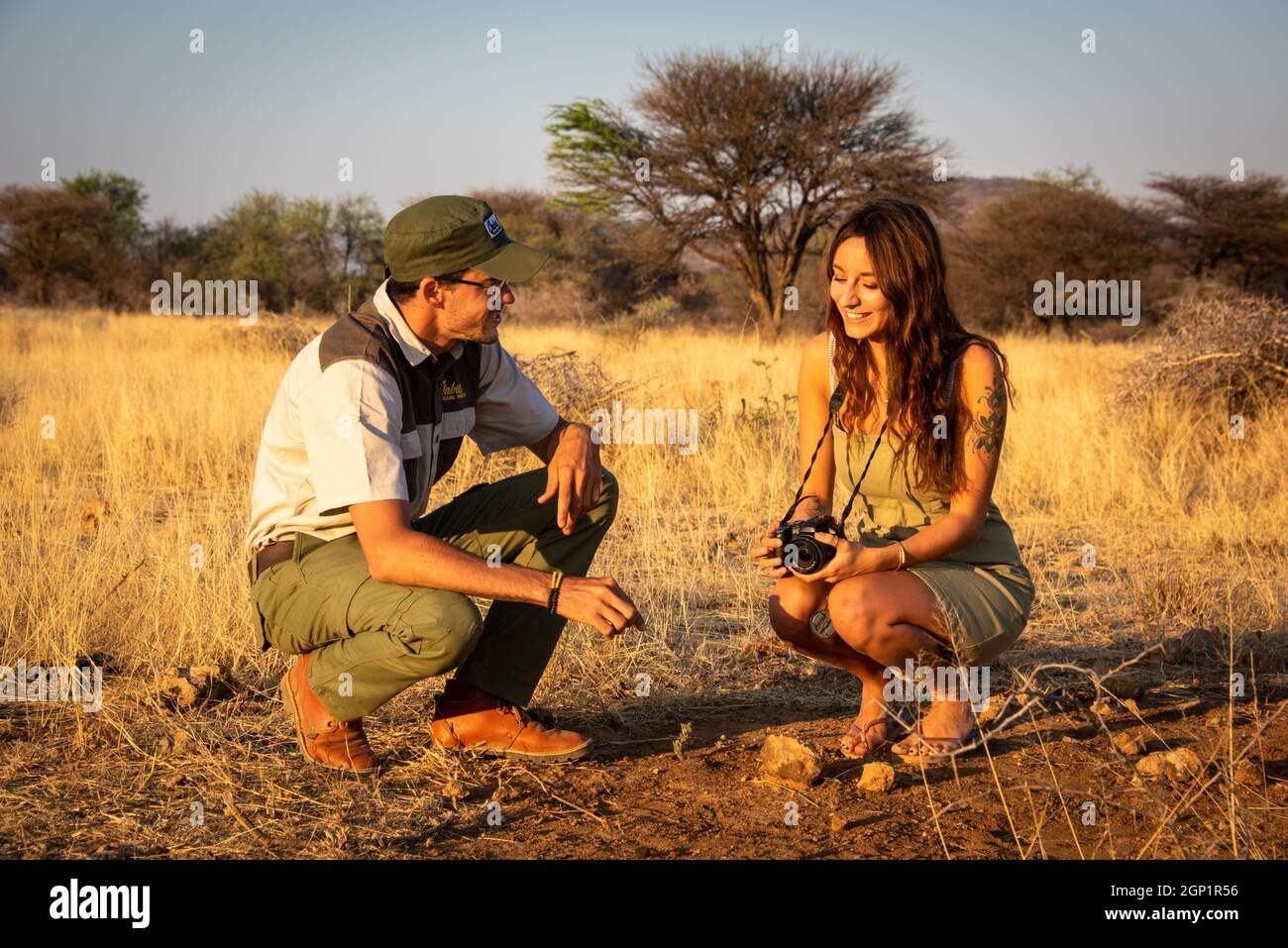 Guide and brunette talk squatting on ground Stock Photo