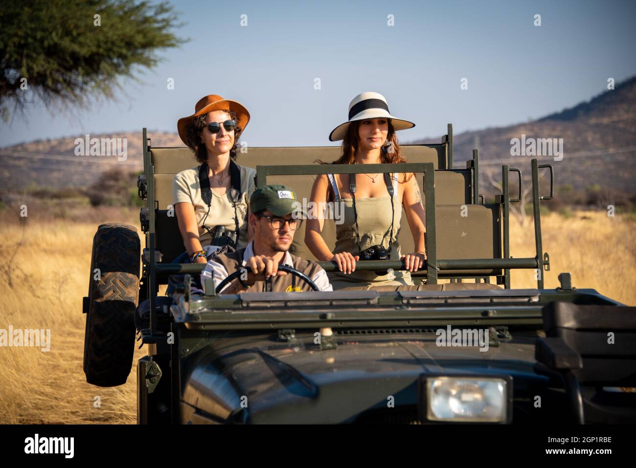 Guide drives two female guests past tree Stock Photo