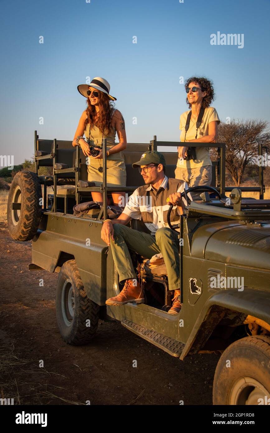 Guide sits with smiling women in jeep Stock Photo