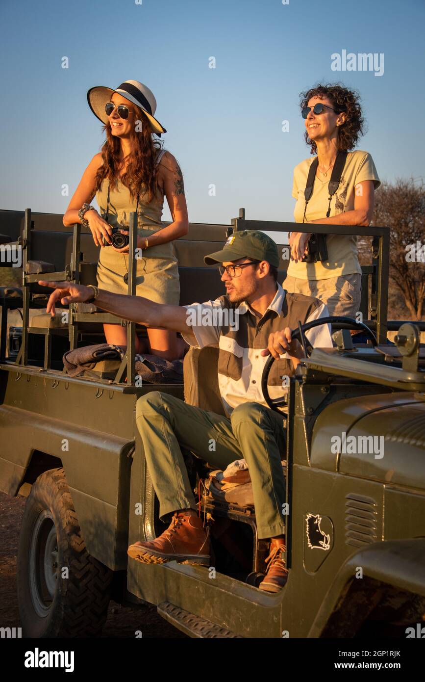 Guide sits pointing with women in jeep Stock Photo