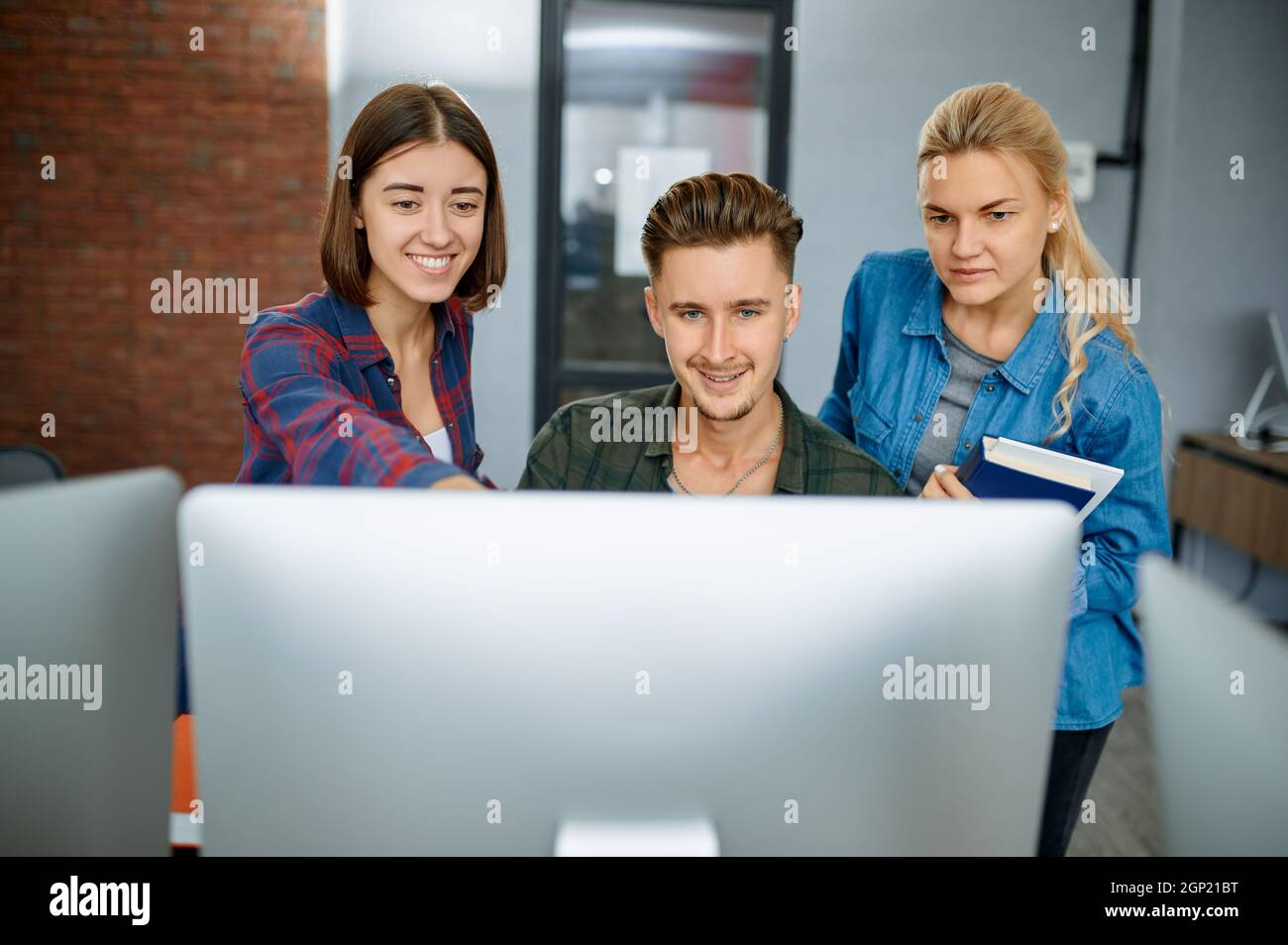 Smiling IT specialists works on computers in office. Web programmer or designer at workplace, creative occupation. Modern information technology, corp Stock Photo