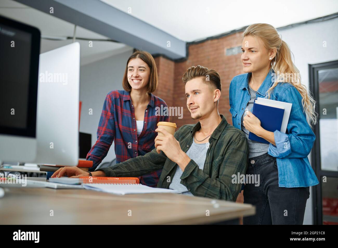 Smiling IT specialists works on computers in office. Web programmer or designer at workplace, creative occupation. Modern information technology, corp Stock Photo