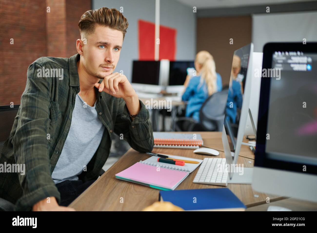 Thoughtful male IT specialist sits at the table in office. Web programmer or designer at workplace, creative occupation. Modern information technology Stock Photo