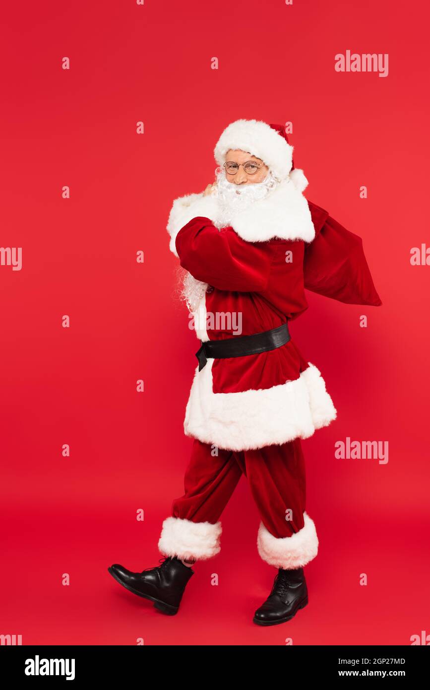 Santa claus with sack walking on red background Stock Photo