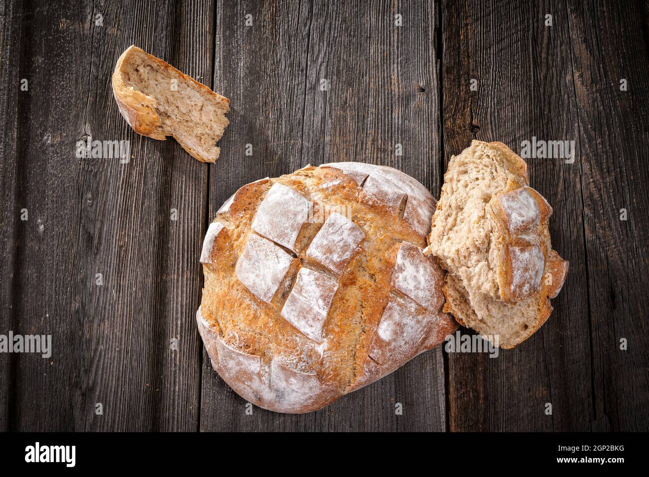 Country bread with floured crust with pieces of crumb on a barn wood