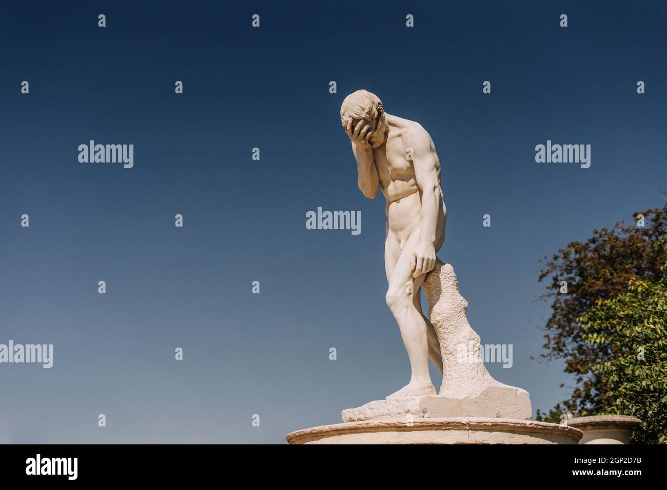 Marble statue making a facepalm gesture against sky Stock Photo