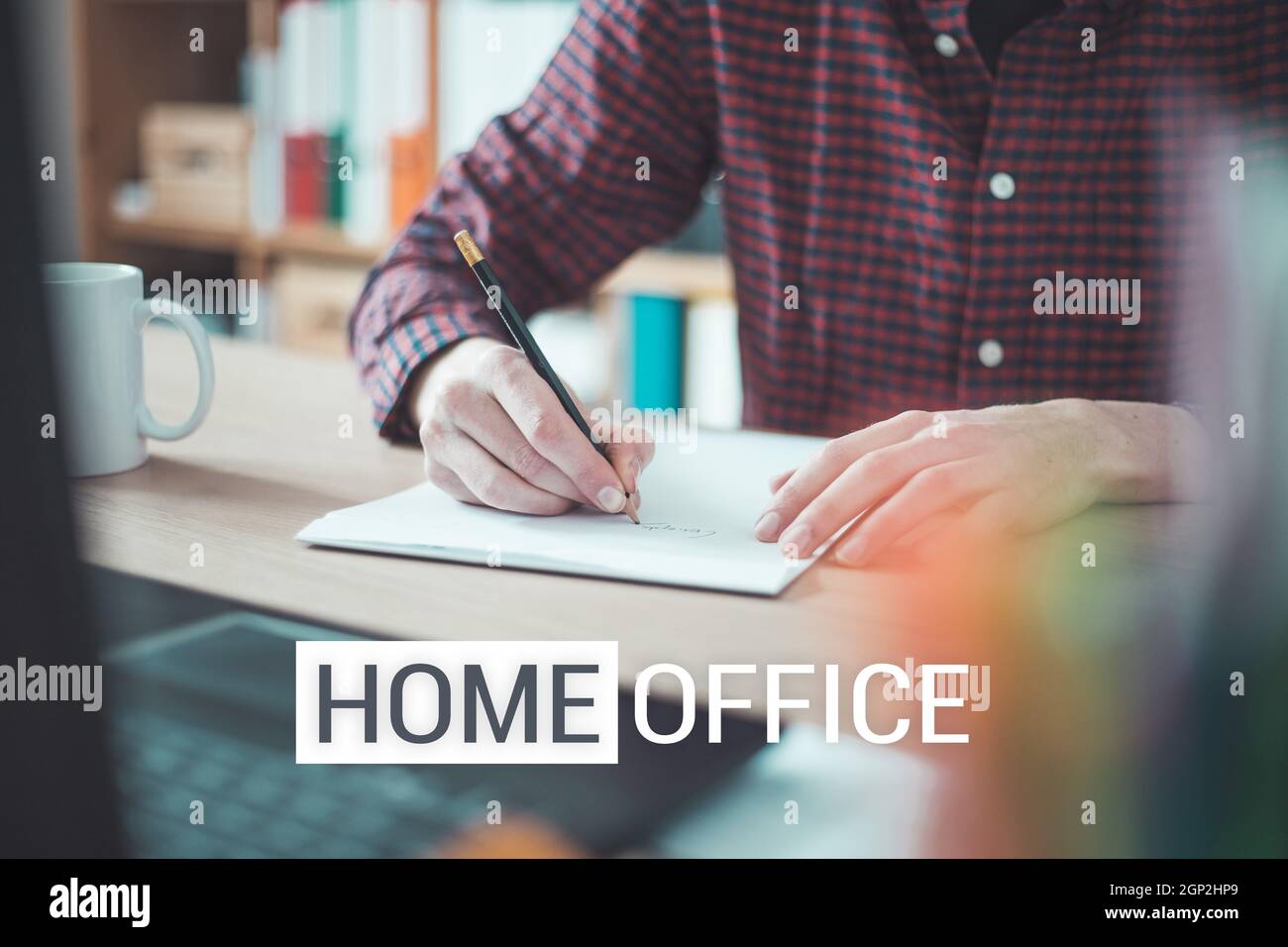 Young man writing on a white sheet, indoor at home office, Text "Home