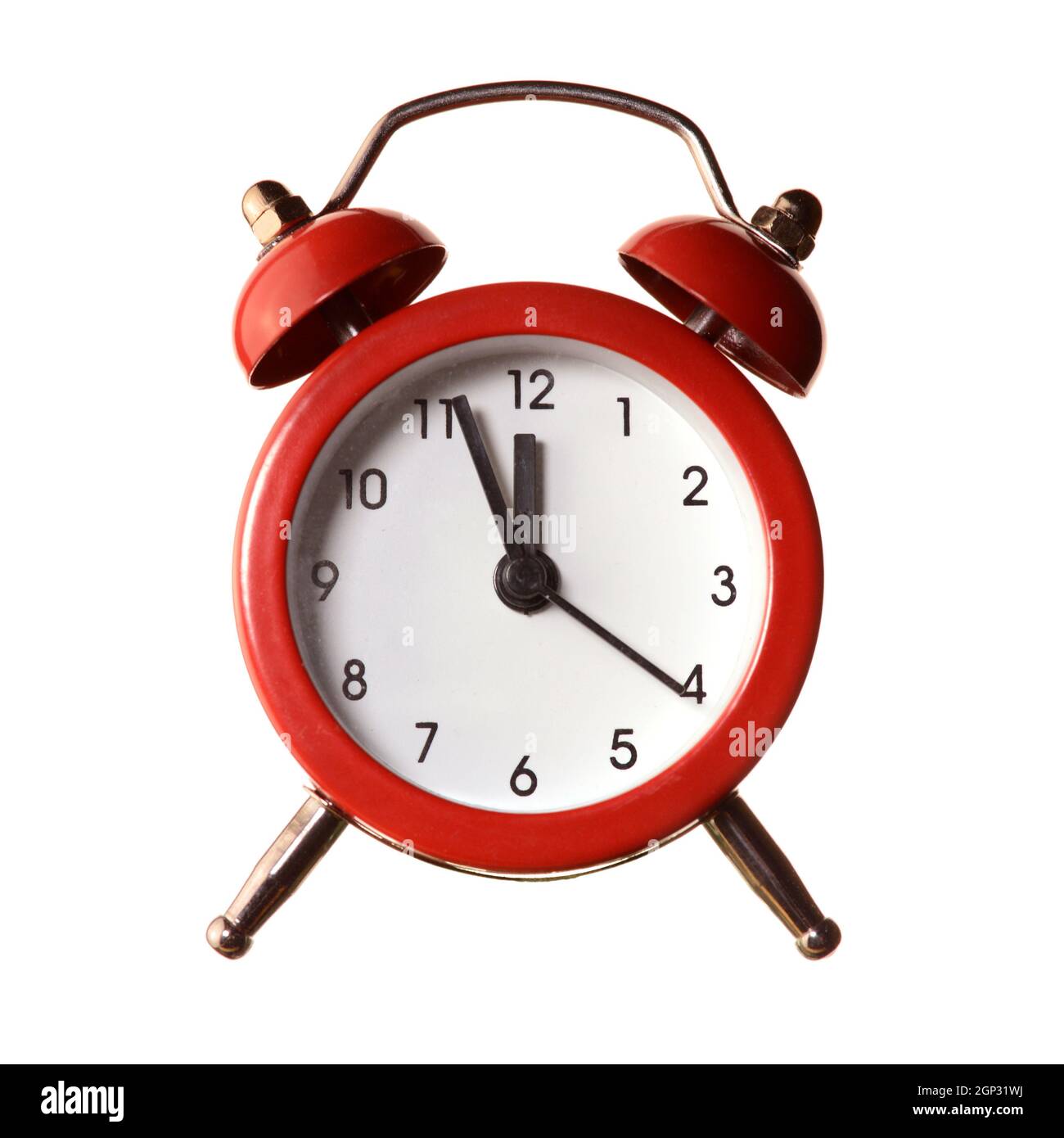 An isolated over white background image of a red alarm clock displaying a time of five minutes to twelve oclock. Stock Photo