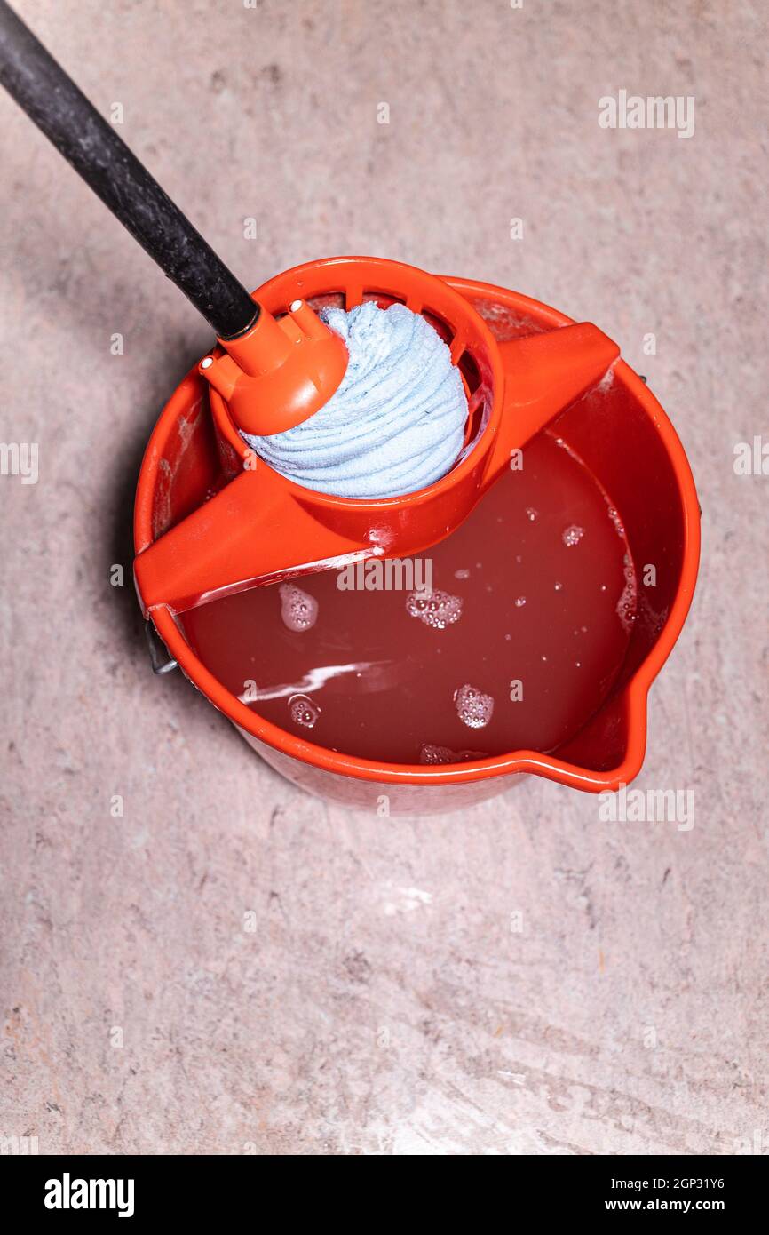 top view of squeezing mop in red bucket with dirty water at home Stock