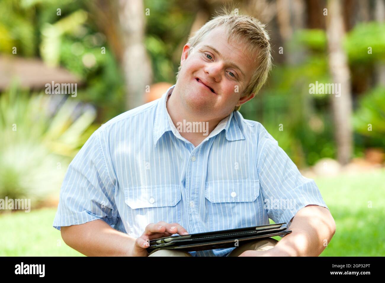 Close up portrait of handicapped boy playing on digital tablet outdoors. Stock Photo