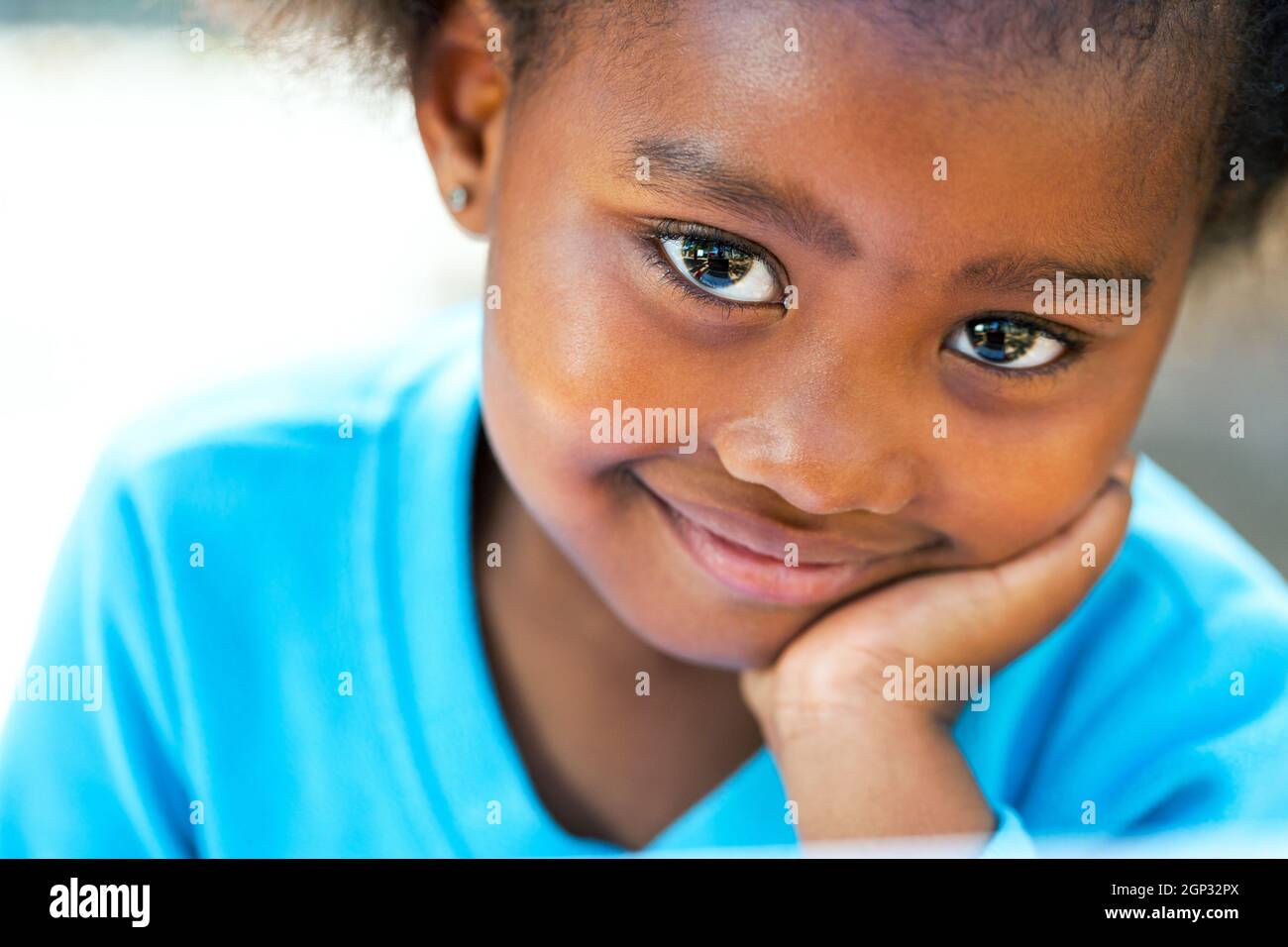 Facial portrait of cute African girl resting cheek on hand. Stock Photo
