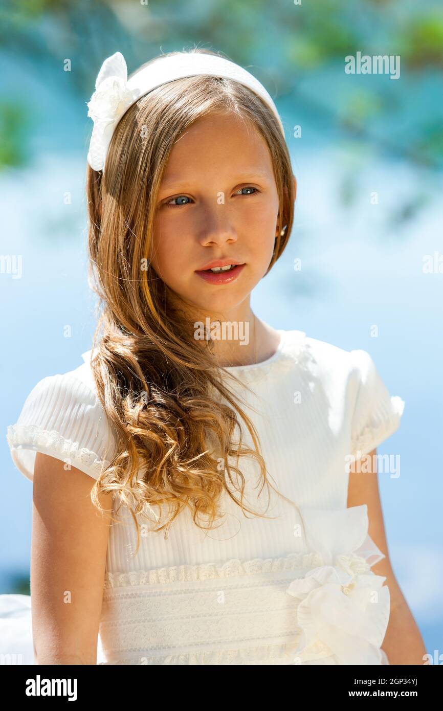 Close up portrait of cute girl in white dress and head band outdoors ...