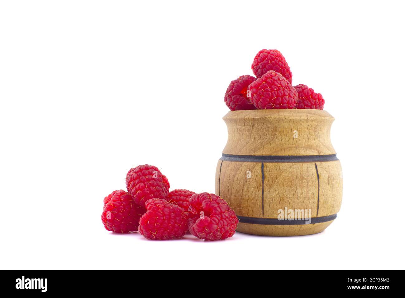 Pile of red ripe raspberry berries and a small wooden pot isolated on ...